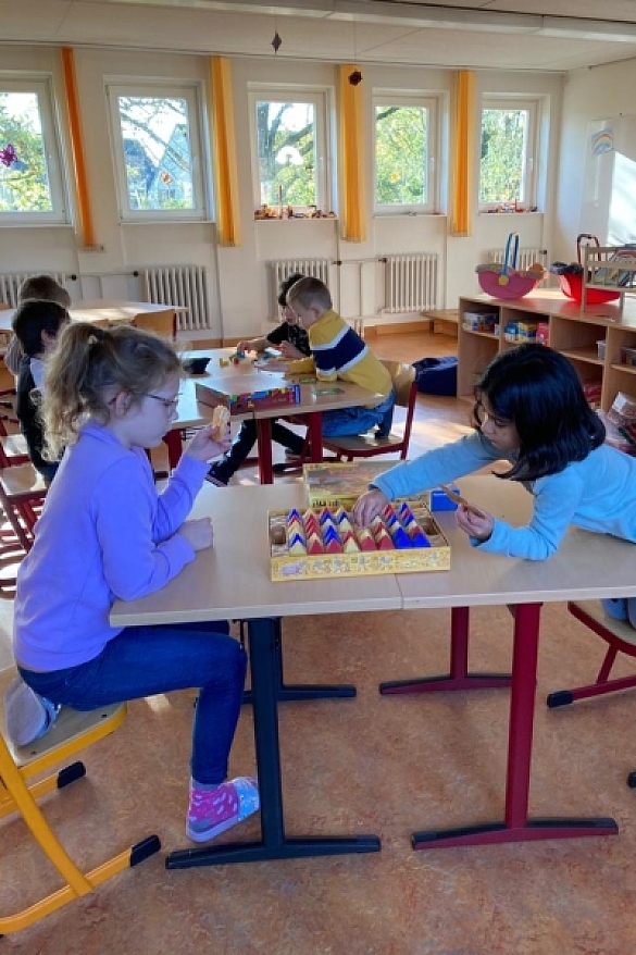 Bild von spielenden Kindern an verschiedenen Tischen