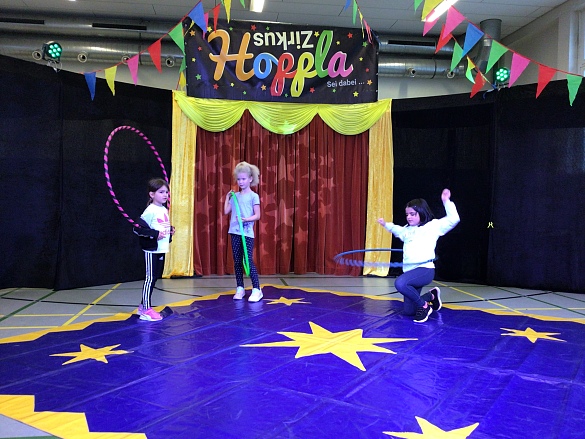 Bild von Kindern mit Hula-Hoop-Reifen in der Manege