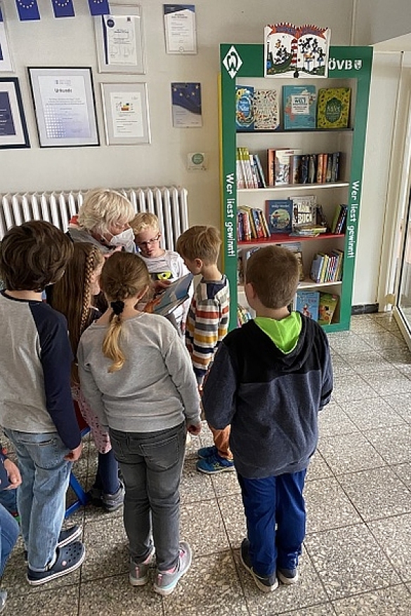 Bild eines Schranks mit Büchern und Kindern davor